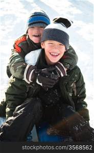 Two young boys smiling in the snow.