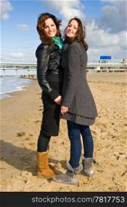 Two young brunette women on the beach on a beautiful autumn afternoon