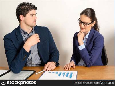 two young business people discussing. Young attractive businesswoman discussing papers with handsome businessman in the office