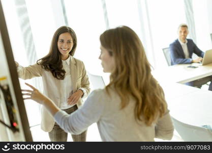 Two young business women discussing financial results on the big wall screen in the office