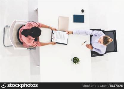Two young business women in meeting at office table for job application and business agreement. Recruitment and human resources concept.