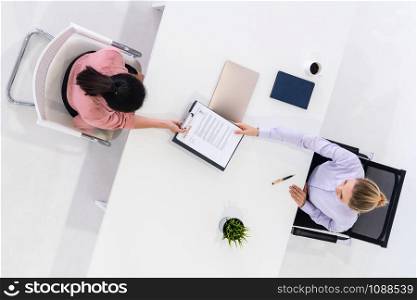 Two young business women in meeting at office table for job application and business agreement. Recruitment and human resources concept.