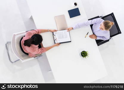 Two young business women in meeting at office table for job application and business agreement. Recruitment and human resources concept.