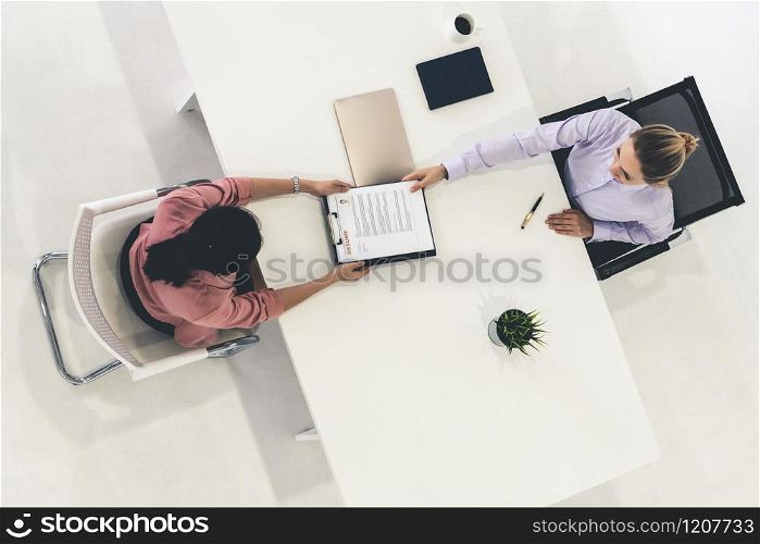 Two young business women in meeting at office table for job application and business agreement. Recruitment and human resources concept.. Two young business women meeting for interview.