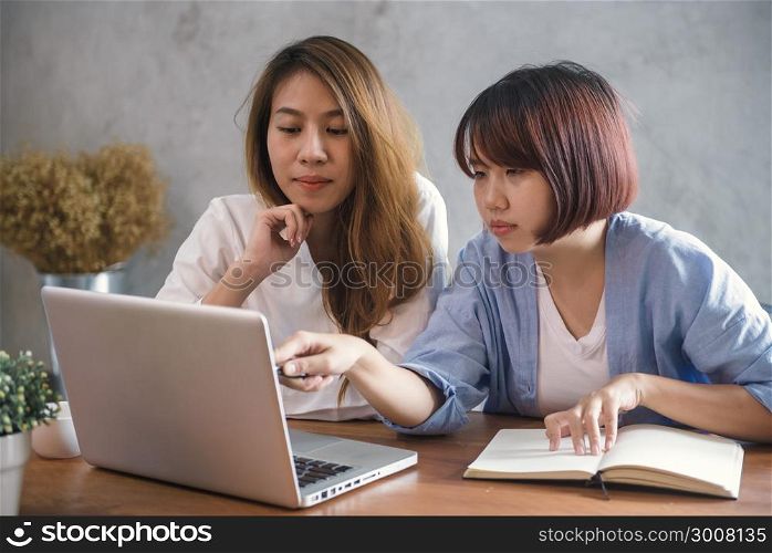 Two young business women sitting at table in cafe. Asian women using laptop and cup of coffee. Freelancer working in coffee shop. Working outside office lifestyle. One-on-one meeting.