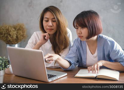 Two young business women sitting at table in cafe. Asian women using laptop and cup of coffee. Freelancer working in coffee shop. Working outside office lifestyle. One-on-one meeting.