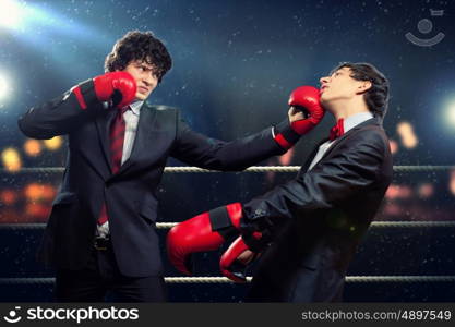 Two young businessman boxing. Two young businessman boxing againts dark background . conceptual collage