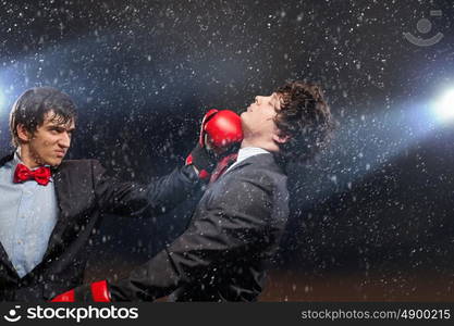 Two young businessman boxing. Two young businessman boxing againts dark background . conceptual collage