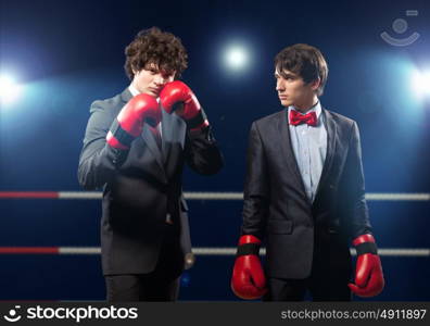 Two young businessman boxing. Two young businessman boxing againts dark background . conceptual collage