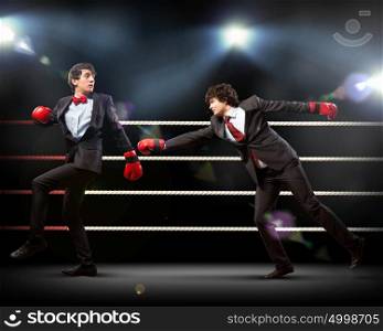 Two young businessman boxing. Two young businessman boxing againts dark background . conceptual collage