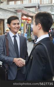 Two young businessman handshaking in houhai, Beijing, China