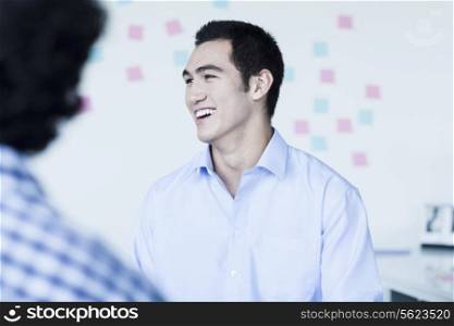 Two young businessman laughing and talking in the office
