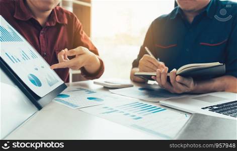 Two young businessman pointing at the earnings profit and analyze together on desk in company room office.