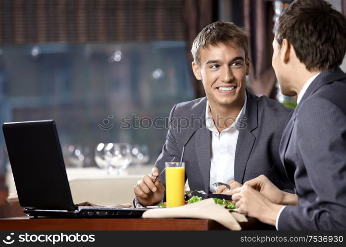 Two young businessmen have supper at restaurant