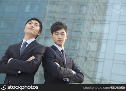 Two young businessmen outside glass building, portrait