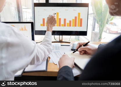 two young businessmen partner explaining information and pointing at report data discussing strategy agreement or contract at office, Teamwork, cooperation