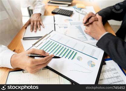 two young businessmen partner explaining information and pointing at report data discussing strategy agreement or contract at office, Teamwork, cooperation