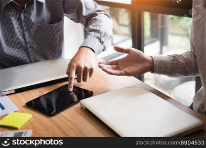 Two young businessmen using touchpad explaining his business plans to his colleagues, organization meeting concept.