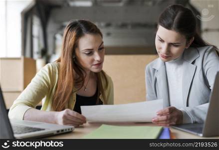 two young businesswoman looking paper office