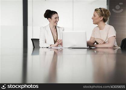 Two young businesswomen having face to face meeting in conference room