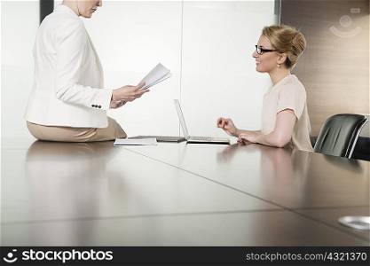 Two young businesswomen meeting face to face in boardroom