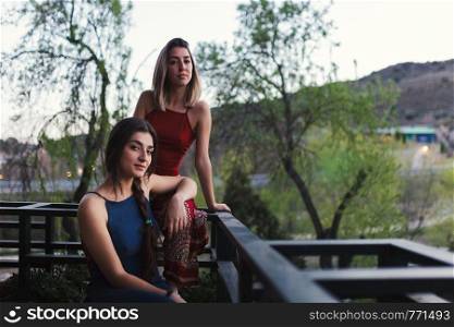 Two young caucasian women watch the sunset from their balcony.