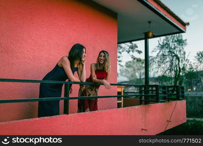 Two young caucasian women watch the sunset from their balcony.