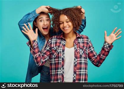 Two young cheerful women, blue background, positive emotion. Face expression, female person looking on camera in studio, emotional concept, feelings. Two young cheerful women, positive emotion