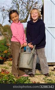 Two young children carrying a heavy watering can in an Autumnal garden