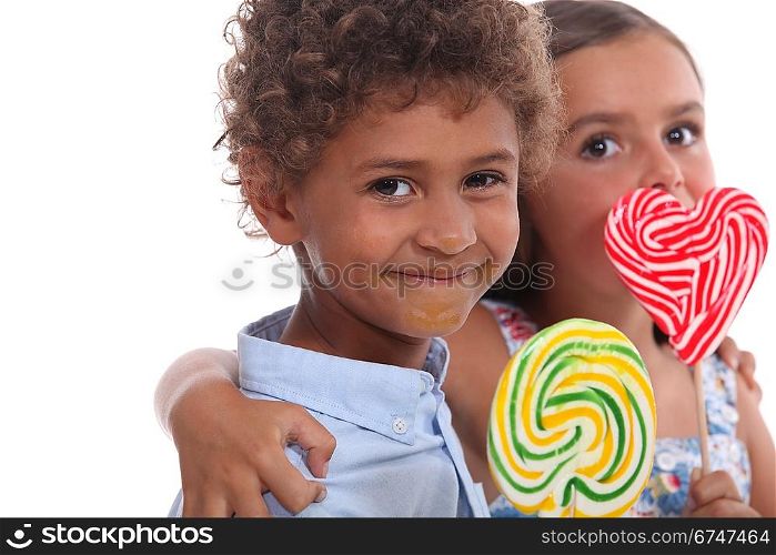 Two young children eating lollipops