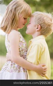 Two young children hugging outdoors