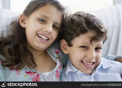 Two young children in living room smiling (high key)