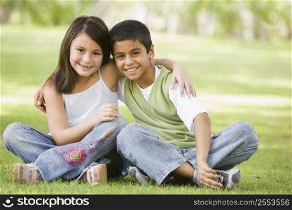Two young children outdoors in park bonding and smiling (selective focus)