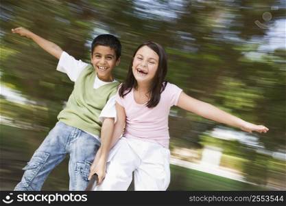 Two young children outdoors in playground spinning and smiling (blur)