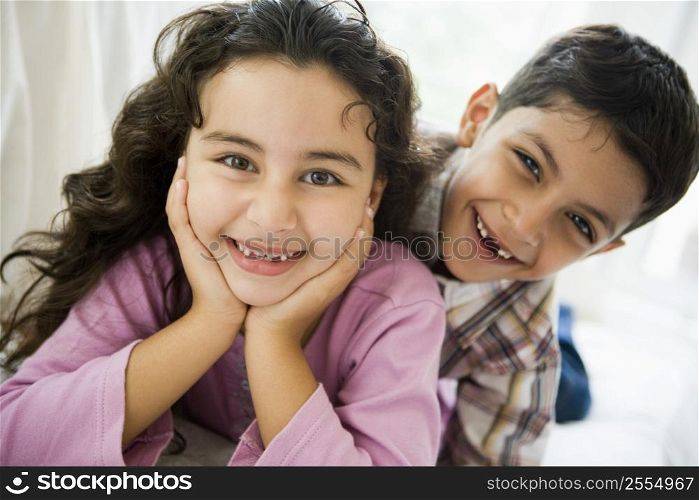 Two young children playing in living room smiling (high key)