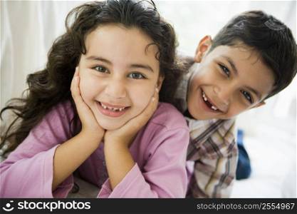 Two young children playing in living room smiling (high key)