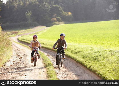 Two young children ride bicycles in park