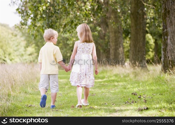 Two young children walking on path holding hands