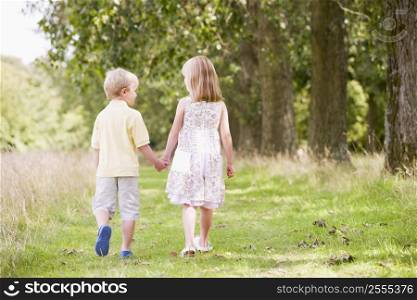 Two young children walking on path holding hands