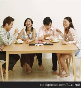 Two young couples eating noodles and smiling