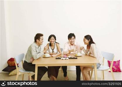 Two young couples eating noodles and smiling
