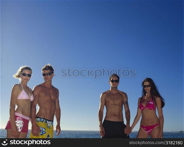 Two young couples holding hands on the beach