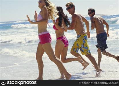 Two young couples running on the beach