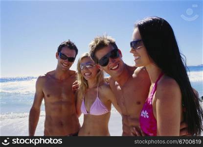 Two young couples standing on the beach