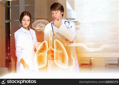 Two young doctors. Image of two young doctors examining virtual image of lungs
