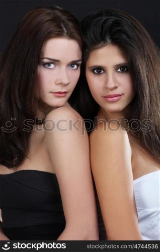 two young embracing friends against dark background