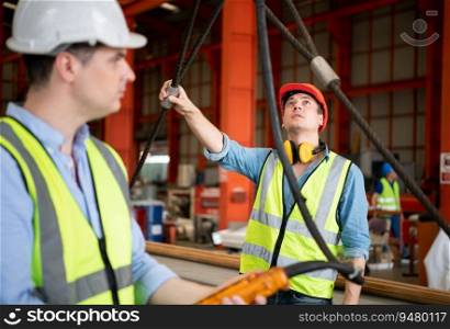 Two young engineers Testing and checking the operation of the over head crane in the factory.