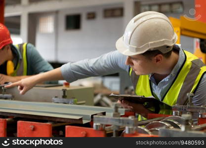 Two young engineers Testing and verifying the operation of the machines forming metal sheet tiles in the factory