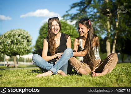 Two young female best friends laughing in park
