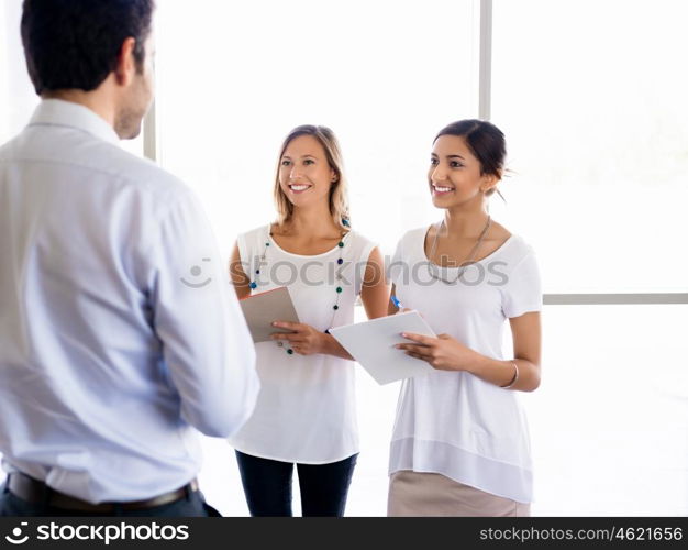 Two young female collegues meeting a new coworker